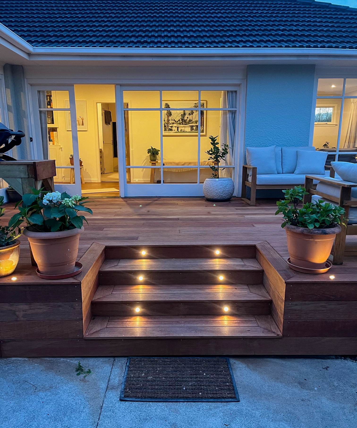 Covered outdoor living area with lit deck steps at twilight
